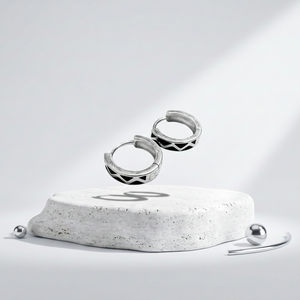 Silver hoop earrings on a white pedestal with 'Elegance in Design' branding.