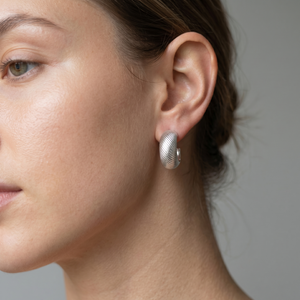 Close-up of a woman wearing silver earrings against a neutral background