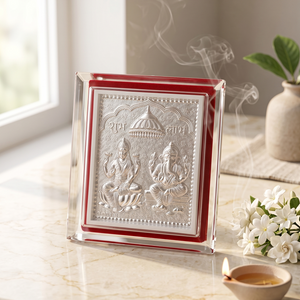 Decorative plaque with religious figures on a marble surface with flowers and a candle.