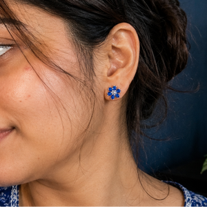 Woman wearing blue floral earrings with a blurred background