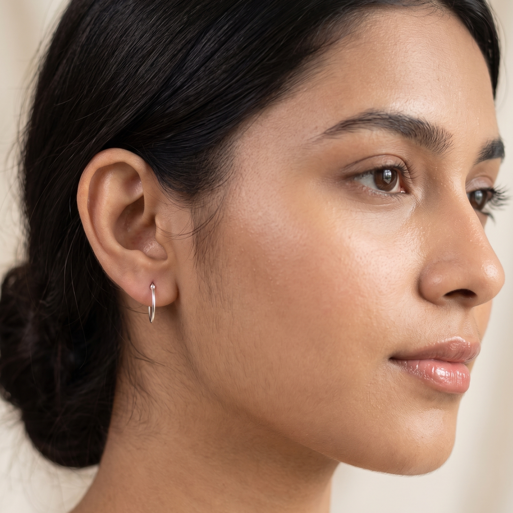 Close-up of a woman's ear with an earring against a neutral background