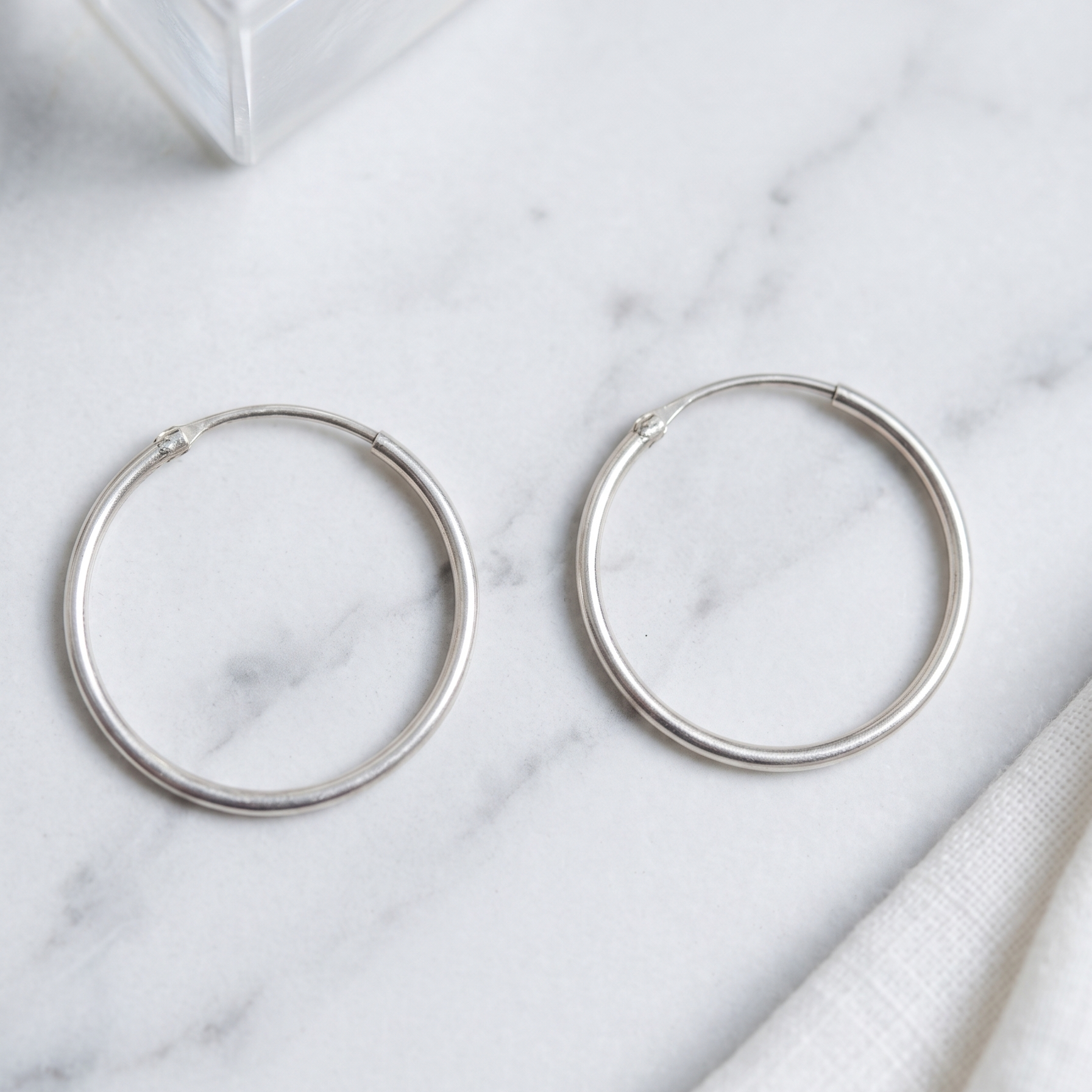 Silver hoop earrings on a marble surface