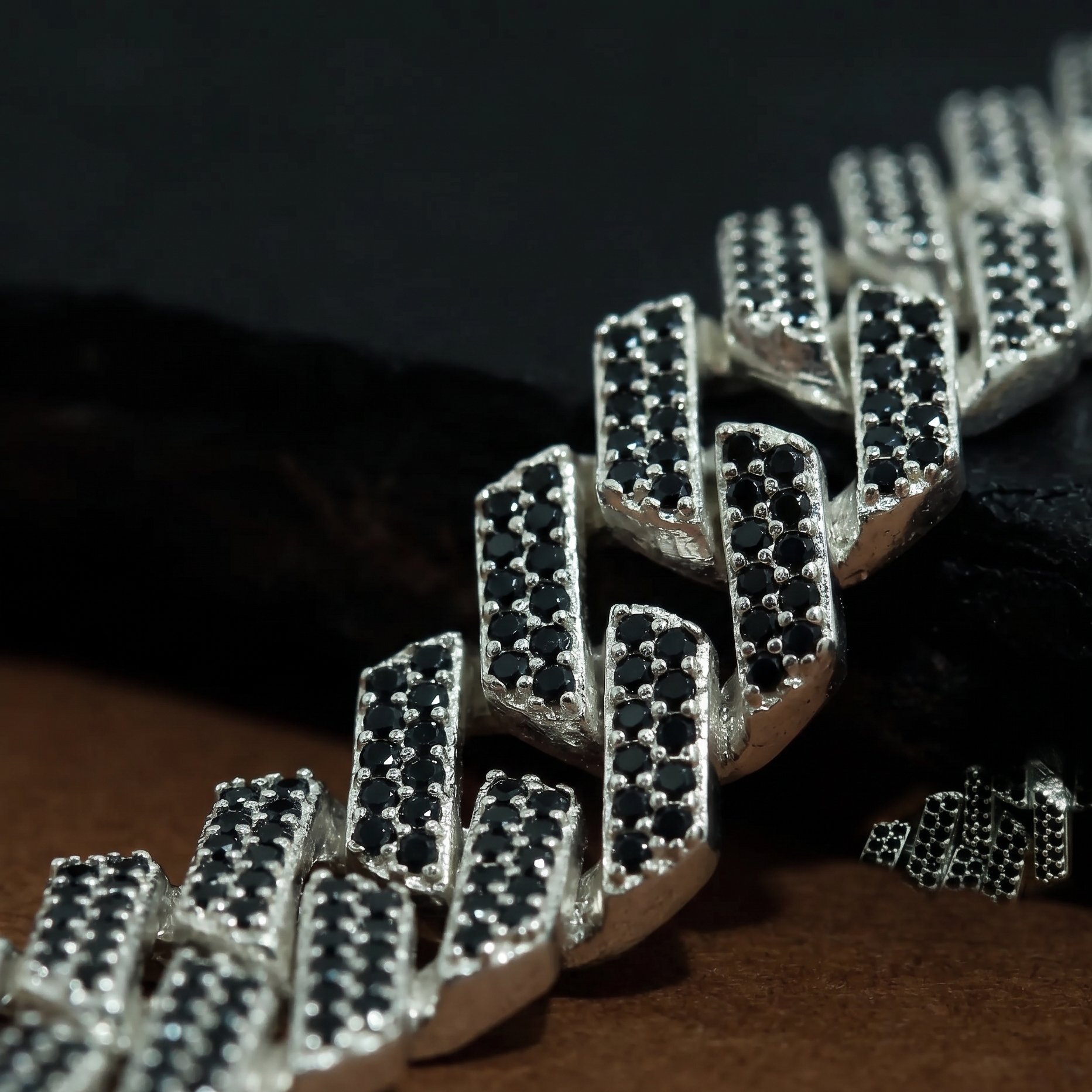 Close-up of a silver chain with diamond-like stones on a dark bracelet