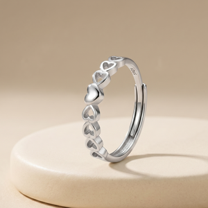 Silver ring with heart designs on a beige background