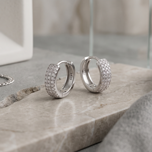 Silver hoop earrings with embedded stones on a stone surface