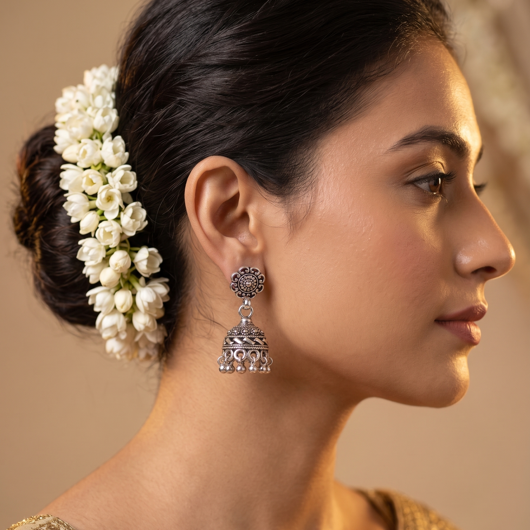 Woman wearing silver earrings with a floral hair accessory against a neutral background