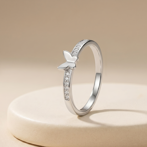 Silver ring with butterfly design on a beige background