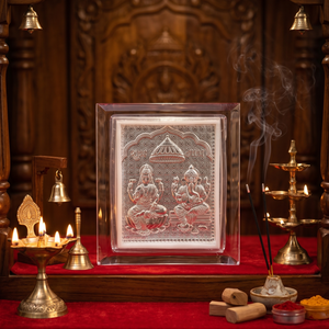 Decorative setting with a silver plaque featuring deities, candles, and incense on a red cloth.
