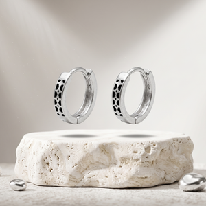 Silver hoop earrings on a stone platform with a neutral background