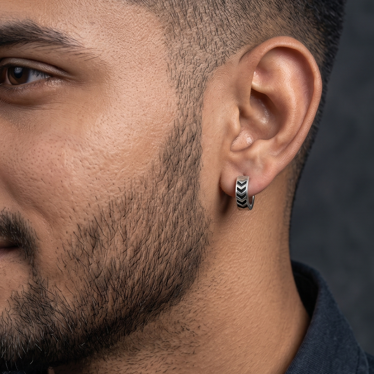 Close-up of a man wearing earrings with a dark background