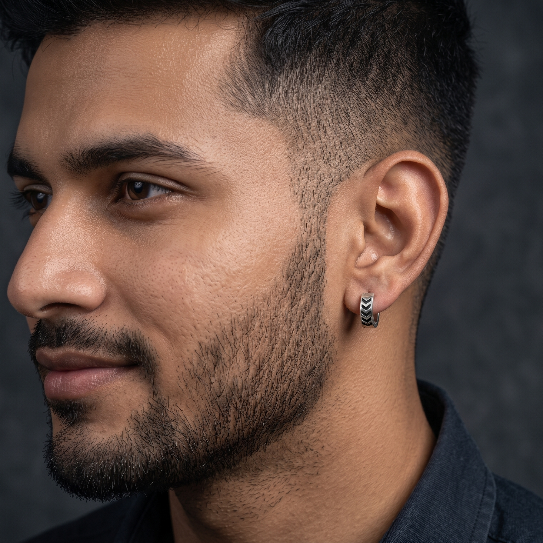 Close-up of a man wearing earrings with a dark background