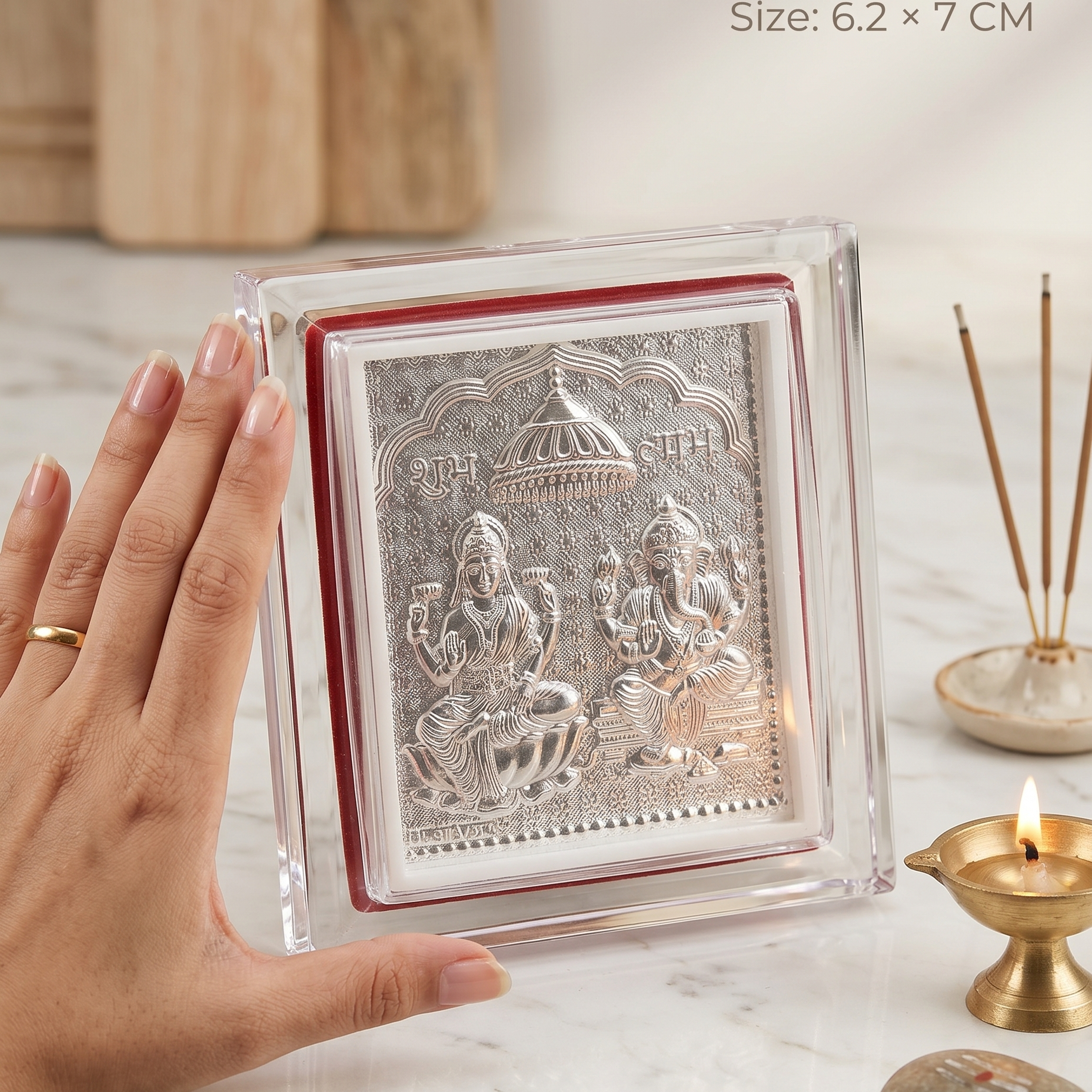 Small silver plaque with figures on a marble surface, hand for scale