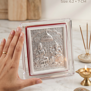 Small silver plaque with figures on a marble surface, hand for scale