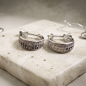 Pair of silver hoop earrings on a textured surface