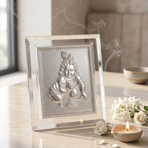 Silver framed deity statue on a table with flowers and a candle
