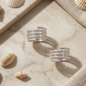 Silver rings on a marble surface with seashells