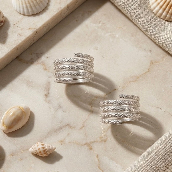 Silver rings on a marble surface with seashells